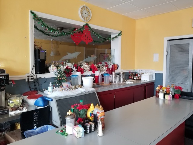 Kim's counter and dining area with buttercup-yellow walls, red booths and chairs, and shelves of teapots, decorated for the holidays